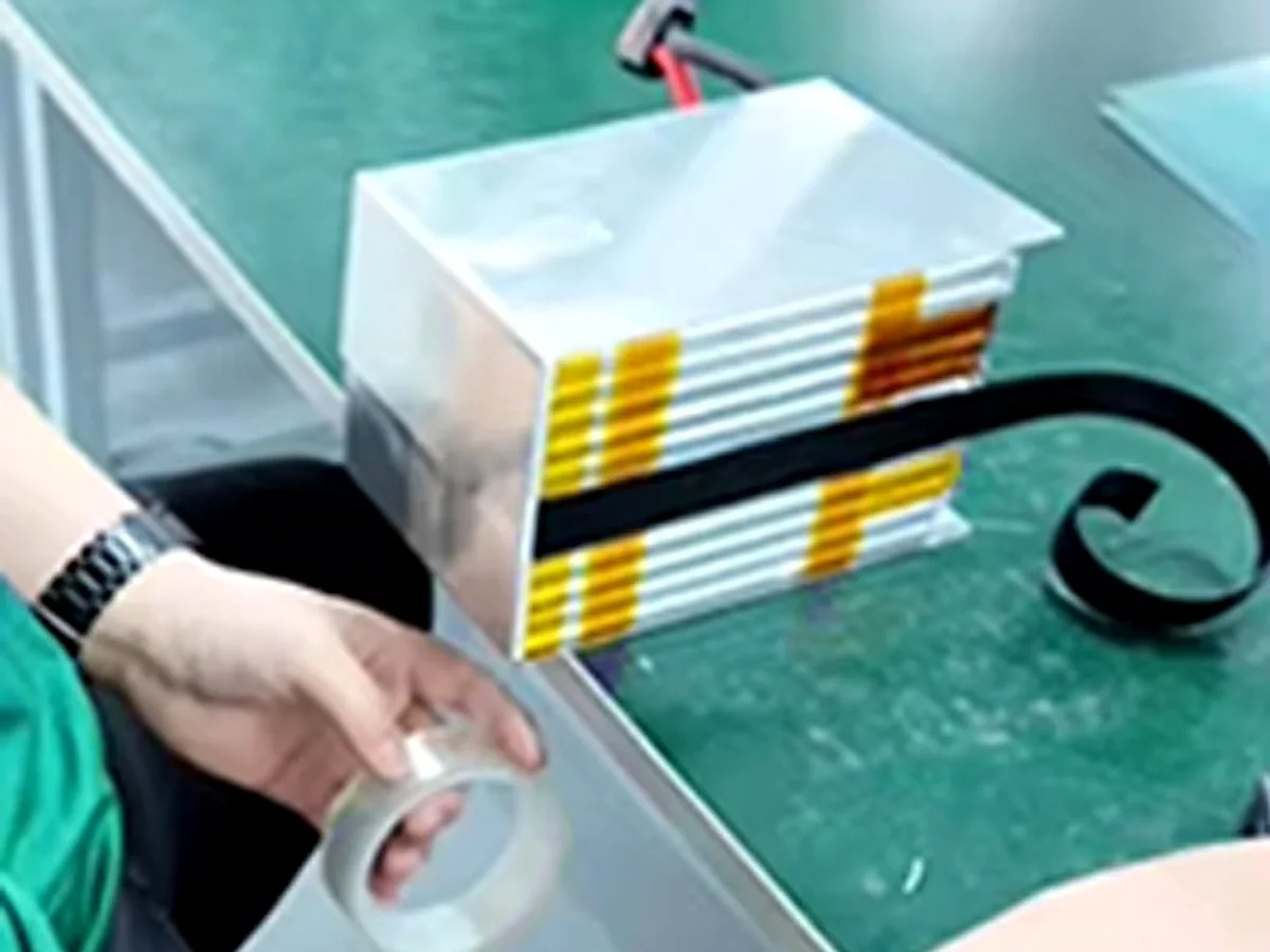 Worker fitting aluminum protection plates onto a battery stack