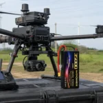 HHPOWER 35000mAh 22.2V solid-state drone battery beside an inspection hexacopter and ground controller at a power line site